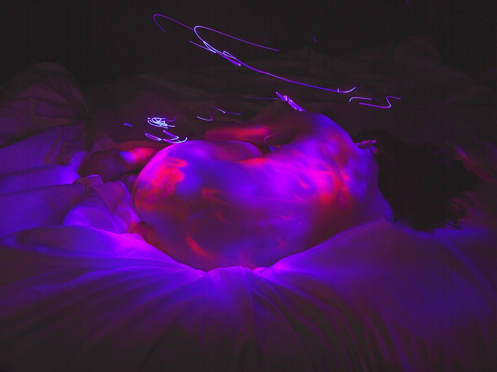 Cuerpos iluminados en azul y violeta en una fotografía de larga exposición